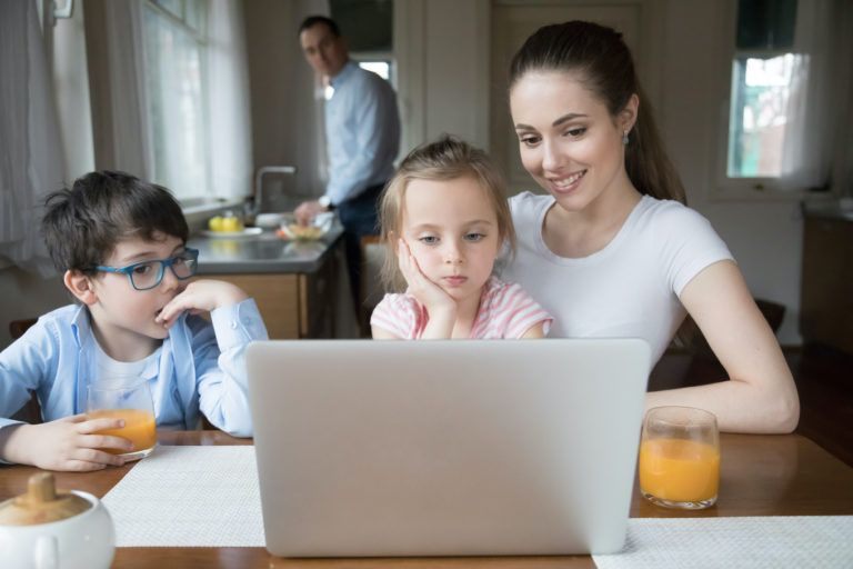 Mother showing cartoon on computer for children while father cooking