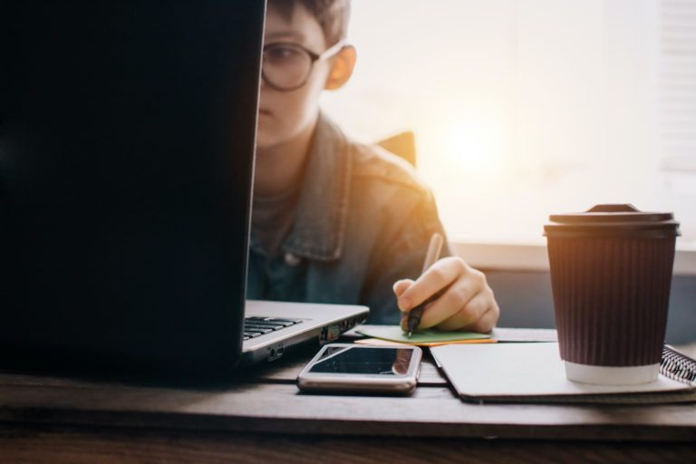 Teenage boy works at desk in his bedroom. School and work concept. Home education. Homework. Home schooling. Working at home.